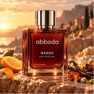 ABBODA NARDO 100ml Eau de Parfum in a red-brown gradient bottle with silver cap, displayed in a warm sunset setting with vanilla, cinnamon, and natural stone.